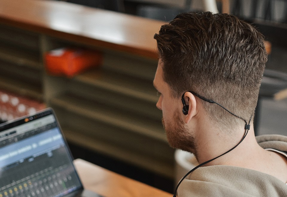 DT 70 IE for Mixing & Critical Listening: In-ear monitor in ear of man at laptop