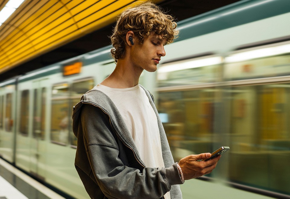 AMIRON 100 - Skater mit AMIRON 100 im Ohr und Handy in der Hand in einer Metrostation 