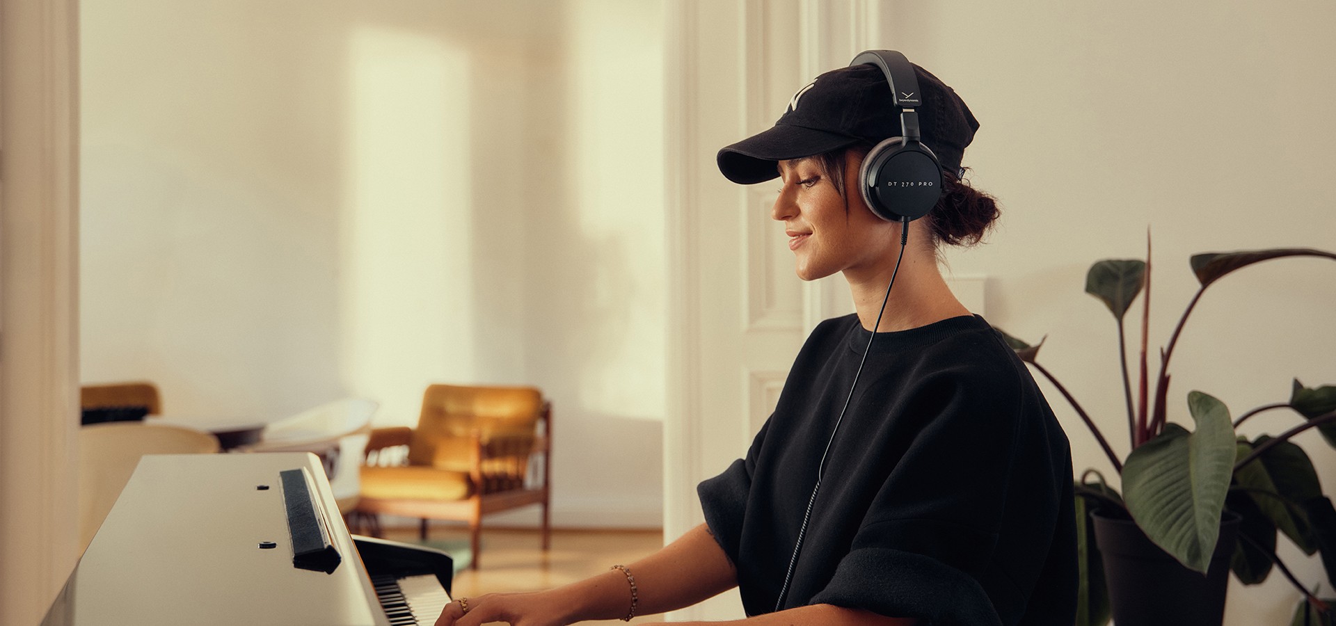Bild mit Frau am Klavier und DT 270 PRO, Studio-Kopfhörer von beyerdynamic auf dem Kopf
