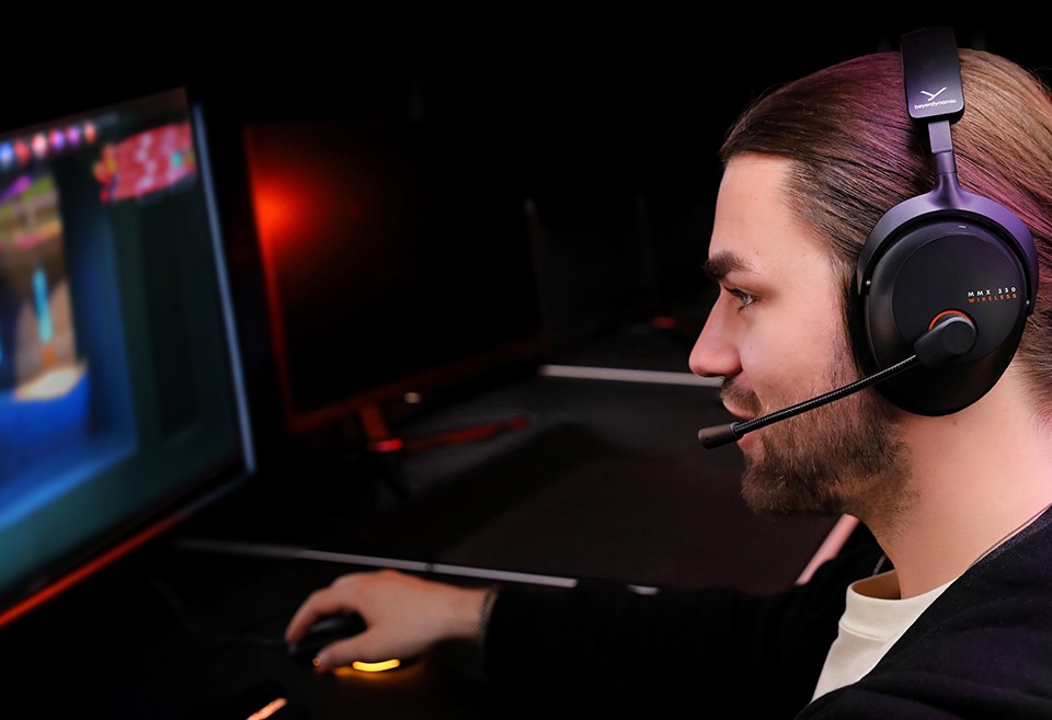 MMX 230 wireless Gaming-Headset auf Kopf eines männlichen Gamers, welcher am PC zockt und in das Headset-Mikrofon spricht. MMX 230 wireless Gaming-Headset auf Kopf eines männlichen Gamers, welcher am PC zockt und in das Headset-Mikrofon spricht.